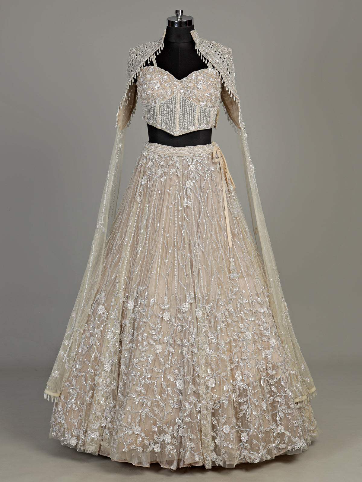 Beige net designer lehenga choli with heavy embellished cape shrug