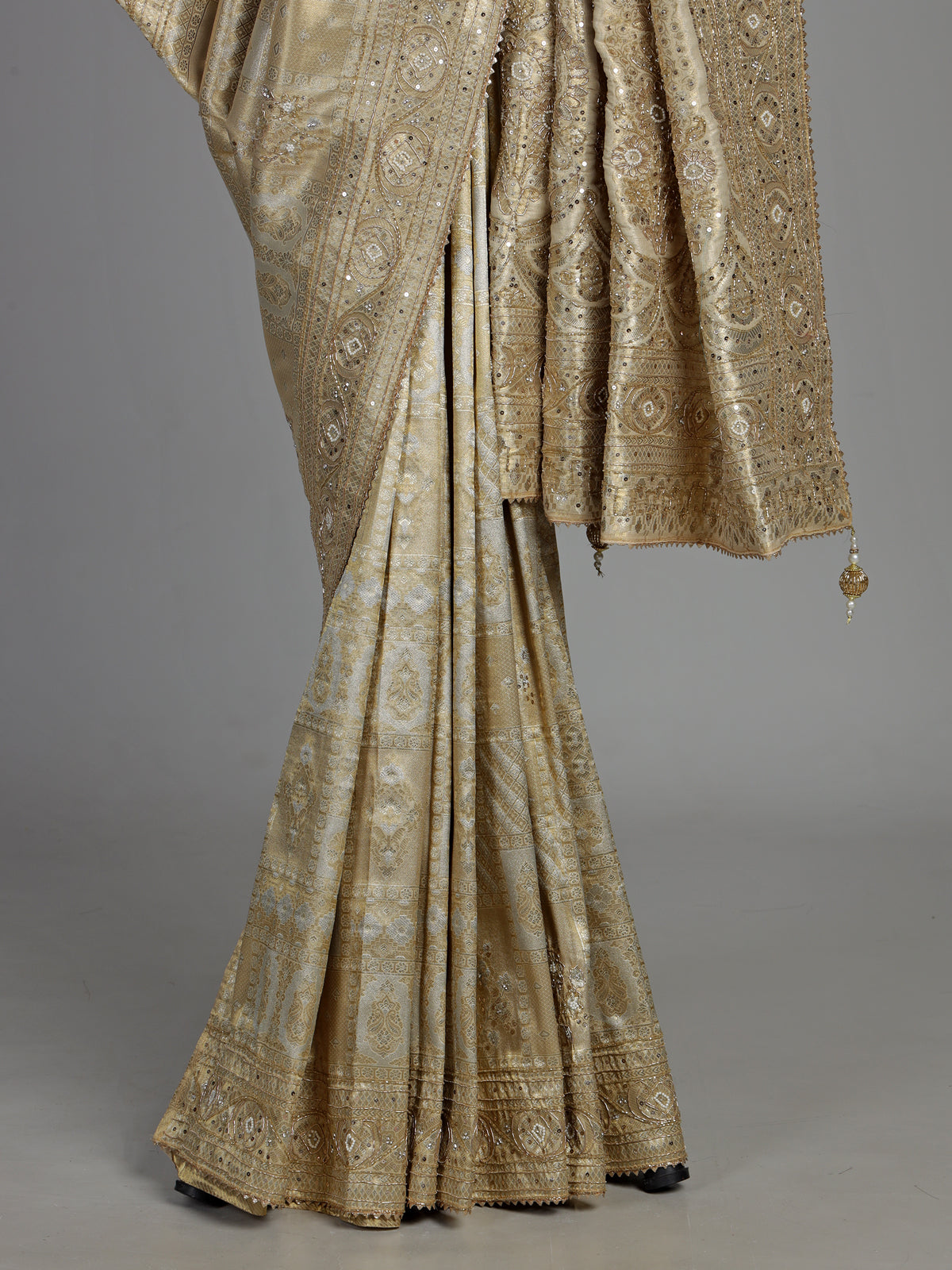 Pastel cream tissue silk saree with intricate festive embellishments and zari