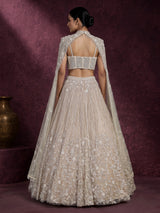 Beige net designer lehenga choli with heavy embellished cape shrug