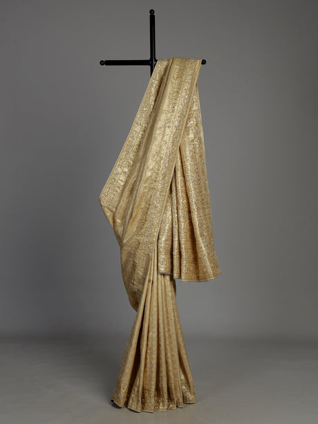 Cream tissue silk saree with mirror accents and intricate festive embroidery