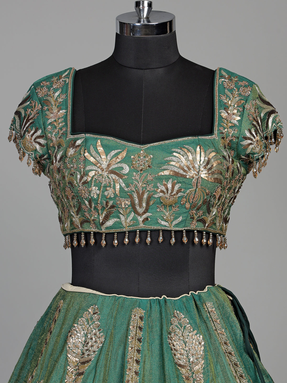 Green silk lehenga choli with intricate zardosi and tassel detailing